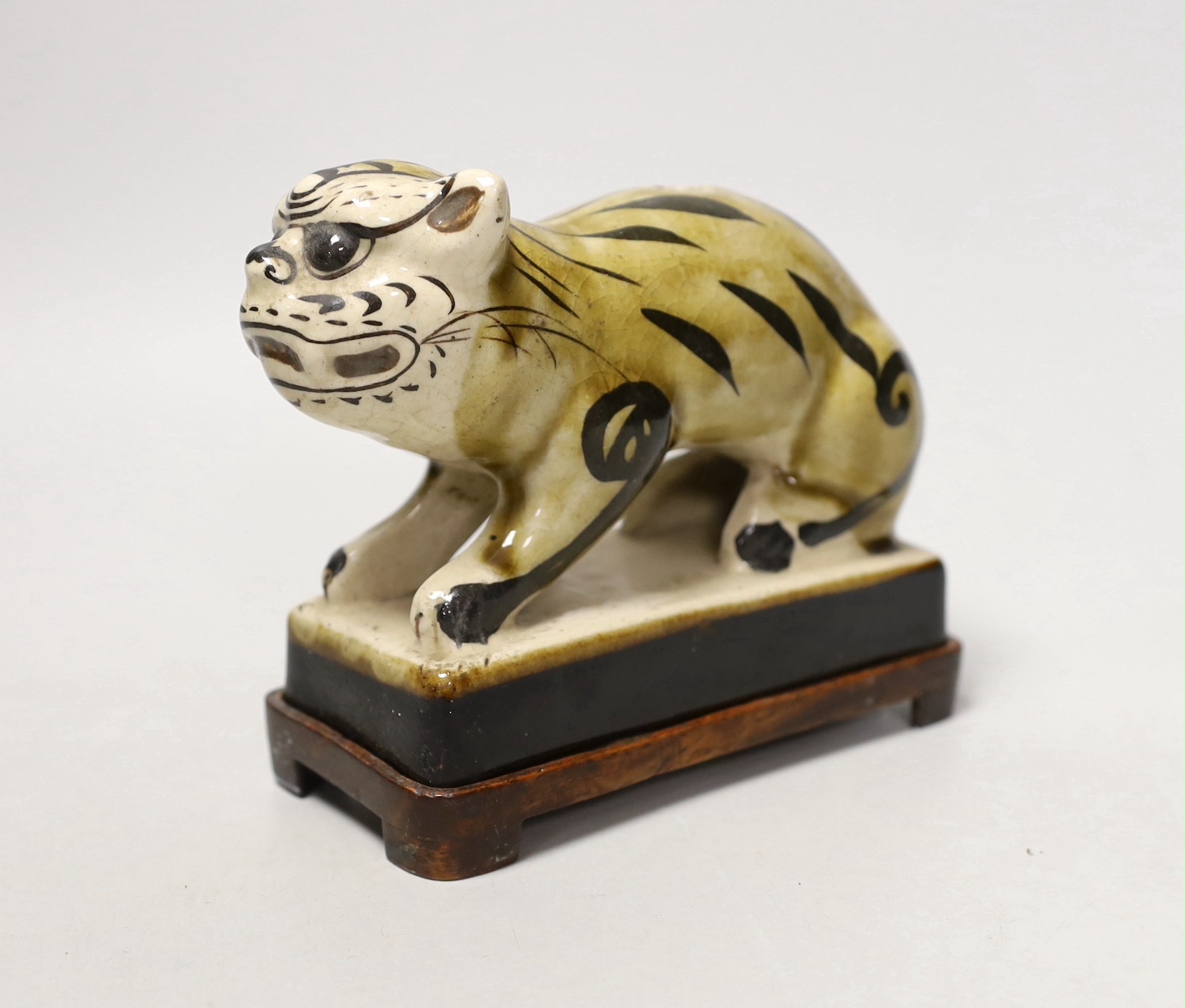 A Chinese Cizhou style pottery ‘tiger’ incense stick holder on wood stand, 13cm tall